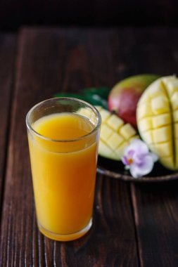 Arka planda mango meyveleri olan taze tropikal mango suyu.