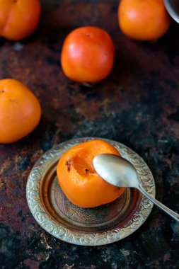 Hurma, gümüş tabak ve kaşıkla yemeye hazır.