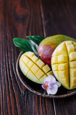 Taze olgun mango yaprakları ve ahşap masanın üzerinde çiçek..