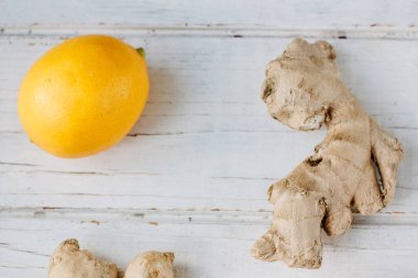 Beyaz yüzeyde sarı limon ve zencefil kökü.
