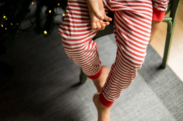 Elf gibi giyinmiş bir çocuk sandalyede oturuyor.