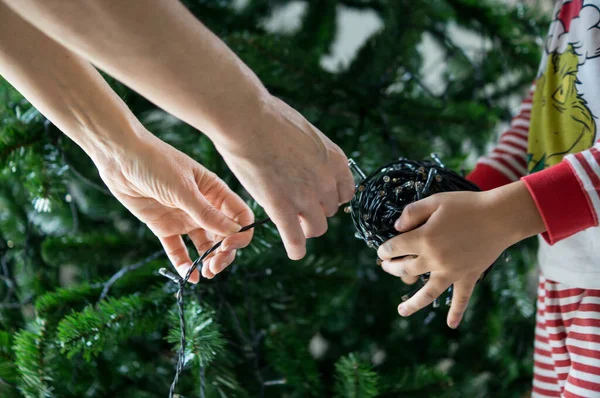 Anne ve oğul evde birlikte Noel ağacı süslüyorlar.