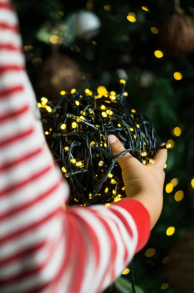 Ağacı süsleyen, ışık saçan bir çocuk