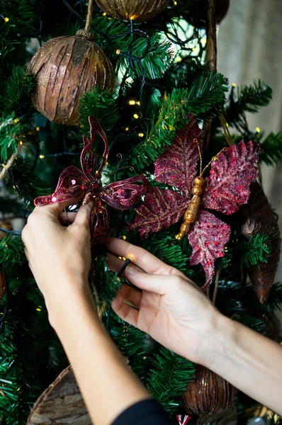 Kadın Noel ağacını oyuncaklarla, yeni yılla ve mutlu noel konseptiyle süslüyor. Kapat - kapat.