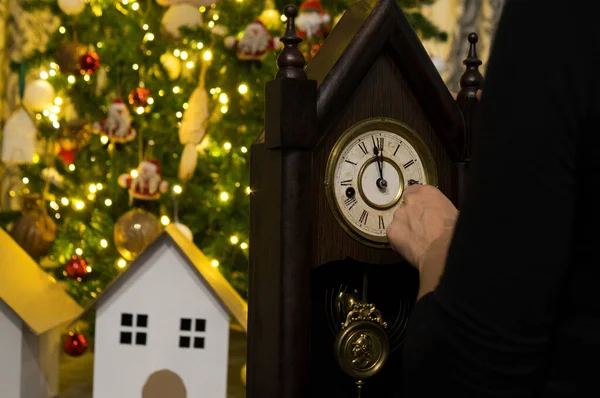 Adam arka planda saat ve Noel süslemeleri tutuyor.