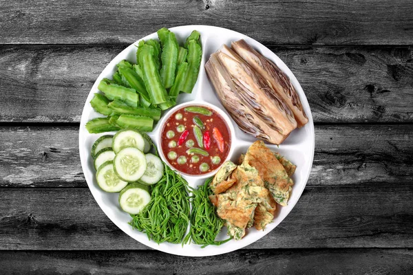 Isolated of Thai popular food,Spicy shrimp paste dip as Nam Prik Kapi in Thai served with winged bean,vegetable omelet,acacia,banana blossom and sliced cucumber. Have text space on right.