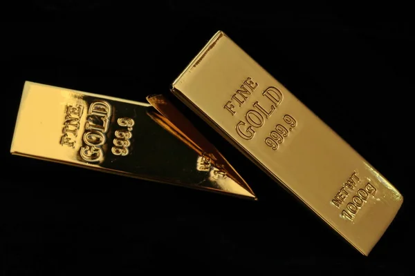 1 kg ağırlığında altın külçeleri 2 sopa karanlıkta, seçici odak yığılmış..