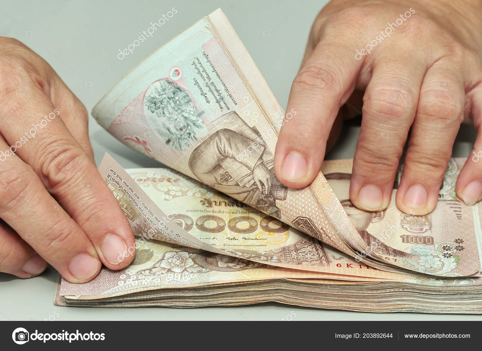 用双手一起计算泰国钞票的1000泰铢的数量——图库图片© SmileKorn #203892644