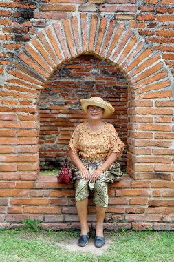 Lopburi, Tayland, 30 Temmuz 2018, kadın turist yaşlı Tay elbise, Saray balkon pencerede oturuyor. Phranarairatchaniwet Kraliyet Sarayı ve Kral Narai Ulusal Müzesi mutlu fotoğraf almak için gülümse .