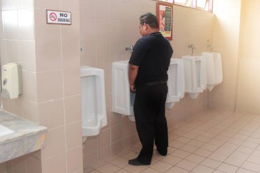 Tak, Tayland, 21 Eylül 2018, idrar bide konferans seminer genel tuvaletler içinde pisuar öfkelenerek için siyah duran adam.
