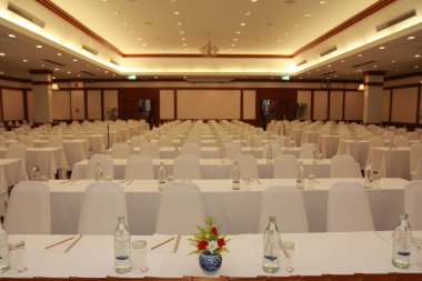 Sandalye yerleşimini bir konferans salonu tarzı tiyatro koltukları yat, bir etek giymiş kırmızı halı ile hazırlayın. Ön yüzünde bulunan mikrofon ile yükseltilmiş alan raflara vardır.