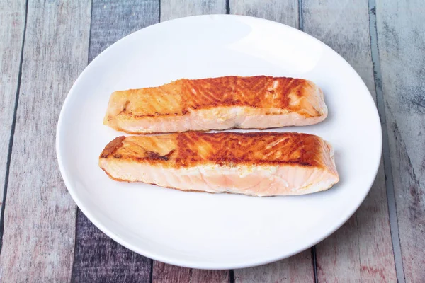 2 gegrilde zalm steaks op wit bord geserveerd op hout. — Stockfoto