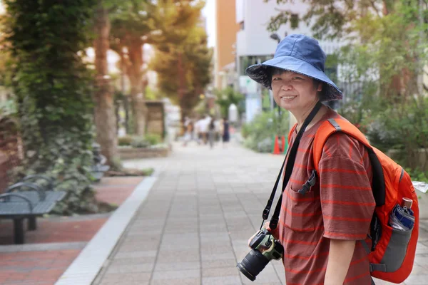 Sonrisa mochila señora turista desgaste jean sombrero, rayas naranja camisa w — Foto de Stock