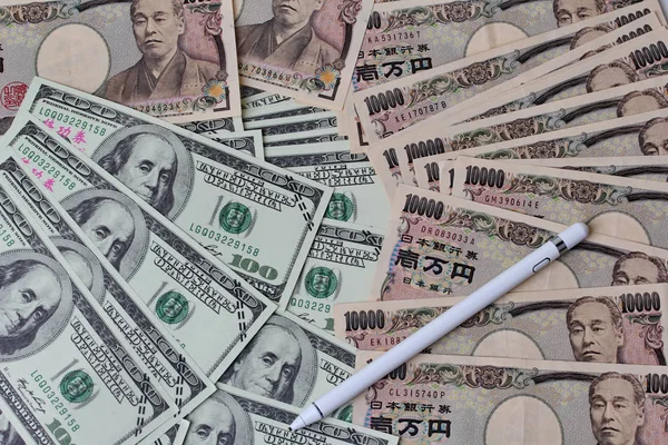 Stylus branco colocar em notas de dólar e iene para o tempo de r — Fotografia de Stock