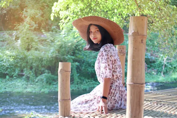 Şapka giyen genç kız oturan ve bir bambu terasta dinlenmek bir — Stok fotoğraf