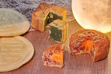 Yuvarlak mooncake dolu 8 taneleri ve tuzlu yumurta ve kare mooncake yeşil çay karıştırılır kırmızı fasulye ezmesi dolu ve çuval bezi üzerine yerleştirilen iki yeşil fasulye mooncakes ile servis doğranmış macadamia fındık
