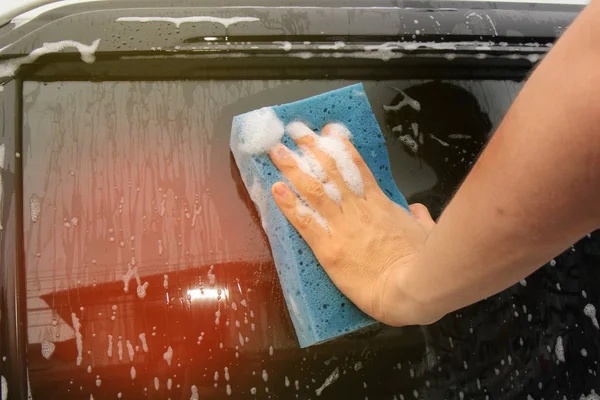 Autowäsche mit Schwamm und Reiniger an Glastür. — Stockfoto