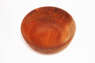 Koyu kahverengi ahşaptan yapılmış küçük boş bir kase beyaz bir zeminde oturur..