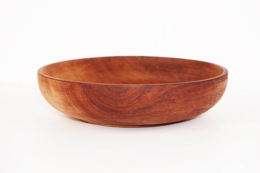 Koyu kahverengi ahşaptan yapılmış küçük boş bir kase beyaz bir zeminde oturur..