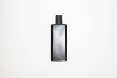 Beyaz bir yüzeye siyah kapaklı mat bir şişe oturur..