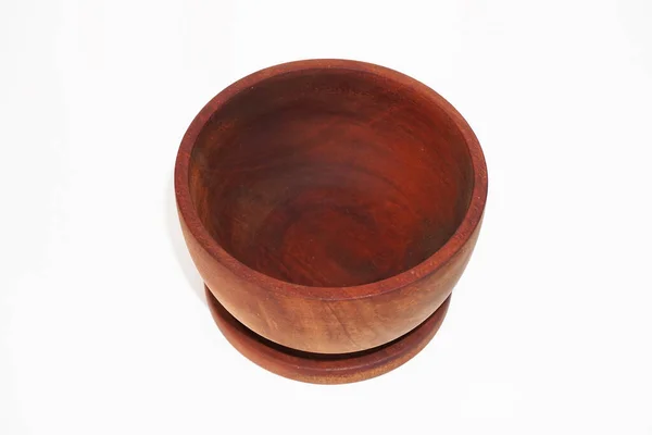 Derin, boş bir ahşap kase küçük bir eşleşen tabakta duruyor..