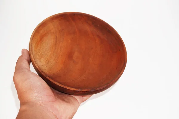 Bir el parlak, koyu kahverengi, ahşap bir kase tutar..