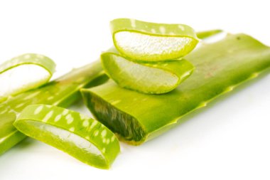 Beyaz arka planda taze, kesilmiş aloe vera yapraklarının makro görüntüsü.