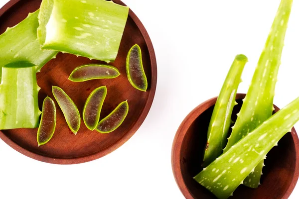 Kahverengi ahşap bir tabak ve kase taze aloe vera bitkisinin çeşitli parçalarını barındırır..