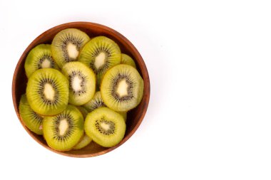 A top-down close-up of a wooden bowl filled with freshly sliced kiwis.
