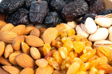 Farklı fındıklar ve kurumuş meyvelerle dolu ahşap bir kasenin yakın çekimi..