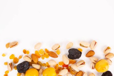 Fındık ve kurutulmuş meyve karışımı beyaz bir arka fonun altına saçılmış..