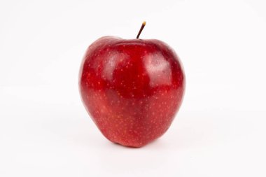 Tek kırmızı elma temiz beyaz stüdyoya genel bir perspektiften parlak dokuyu gösteriyor..