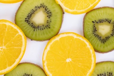 Dilimlenmiş kivi ve turuncu iç içe geçmiş canlı, renkli bir yemek kalıbı oluşturuyor..