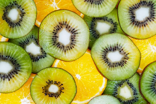 Dairesel kivi dilimleri sulu portakal dilimleriyle örtüşüyor soyut, renkli arka plan ayrıntıları yaratıyor.