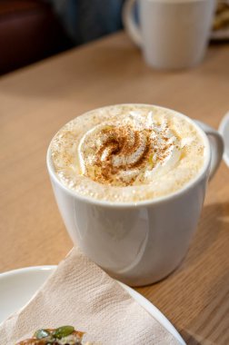 Krem şantili ve ahşap masaya serpiştirilmiş tarçınlı sıcak balkabağı aromalı latte. Yüksek kalite fotoğraf