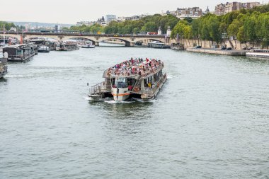 Fransa 'nın başkenti Paris' te güneşli bir günde Seine nehrinde yelken açan bir yolcu gemisi..