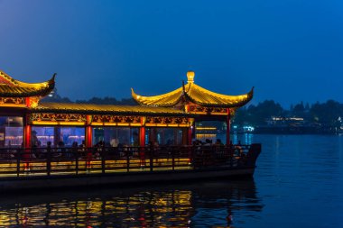 Batı Gölü 'nün gece manzarası, Çin' in Hangzhou kentindeki gölde yelken açan geleneksel Çin yolcu gemisi. Gölün içinde sayısız tapınak, pagoda, bahçe ve yapay adalar vardır..