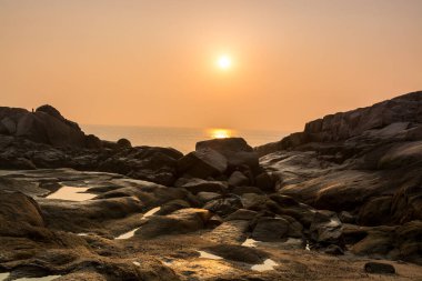 Sabahleyin Putuo Dağı 'nın kıyısında deniz ve taşın üzerinde gün doğumu Zhoushan, Zhejiang, Çin' de Şangay 'ın güneydoğusunda Bodhisattva Guanyin' in Bodhimaa 'sı. 