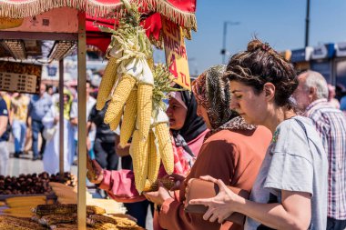 İstanbul, Türkiye 'de Altın Boynuz yakınlarında yer alan İstanbul Boğazı' nın Avrupa yakasında ızgara mısır alan turistler.
