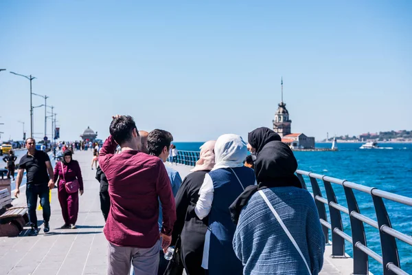 İstanbul, Türkiye 'nin Uskudar kentindeki Corniche parkında, İstanbul Boğazı' nın Anadolu kıyısında yürüyen insanlar. Leander 'ın Kulesi olarak da bilinen Bakire Kulesi' nin arka planına sahip.
