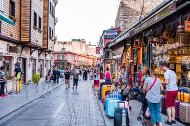 İstanbul, Türkiye 'de turistler yoğun bir yaz gününde ellerinde renkli hediyelik eşya ve kafelerle caddelerde yürüyorlar