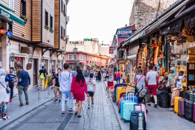 İstanbul, Türkiye 'de turistler yoğun bir yaz gününde ellerinde renkli hediyelik eşya ve kafelerle caddelerde yürüyorlar