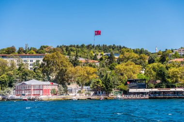 Türkiye 'nin İstanbul kentindeki İstanbul Boğazı' nda yaz mevsiminde, Türk ulusal bayrağı ve yeşil ormanıyla birlikte çok güzel binalar ve malikaneler inşa edildi. Bir Gemi Gezisinden Görünüm.