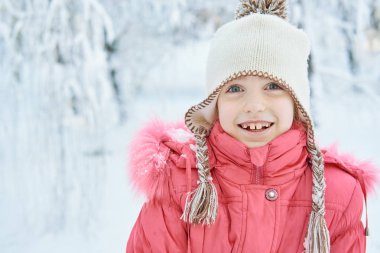 Kışın parkta şapkalı gülümseyen kız.