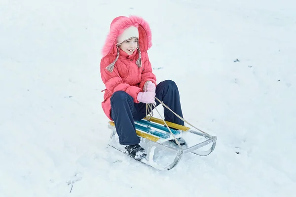 Девушка катается на санках в парке зимой — стоковое фото