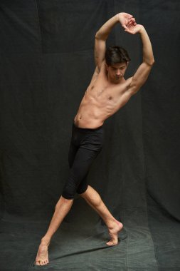 Siyah kumaş arka planında hareket eden genç balerin.