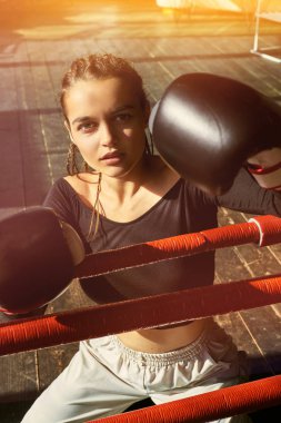 Boks eldivenli kız ringde oturuyor.