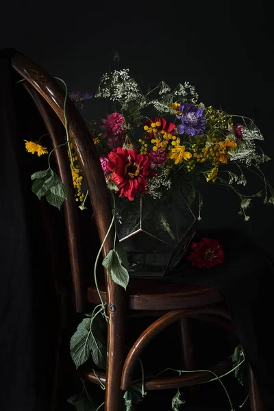Kleurrijk boeket op een houten stoel op een zwarte achtergrond — Stockfoto
