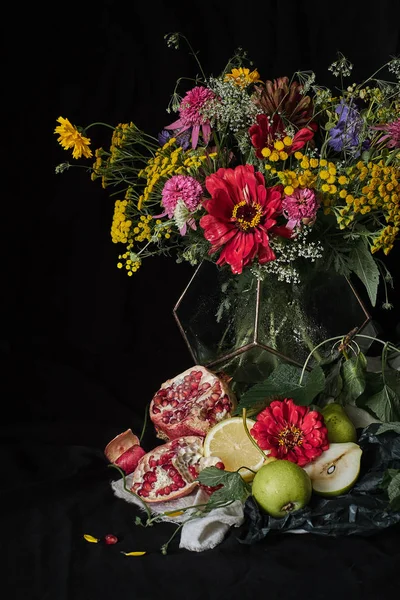 Bouquet of flowers on a black background, next to the fruit