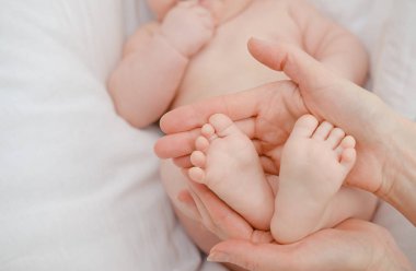 Beyaz arka planda, annesinin ellerinde, yeni doğmuş beyaz ayaklar. Anne ve çocuğu.. 